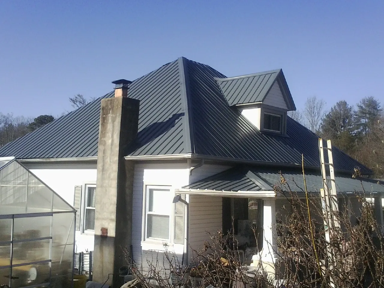 Dark blue standing seam metal roof on a white farmhouse with dormer — Slate & Tile Roof Repair by Roofing Brothers in Herrick