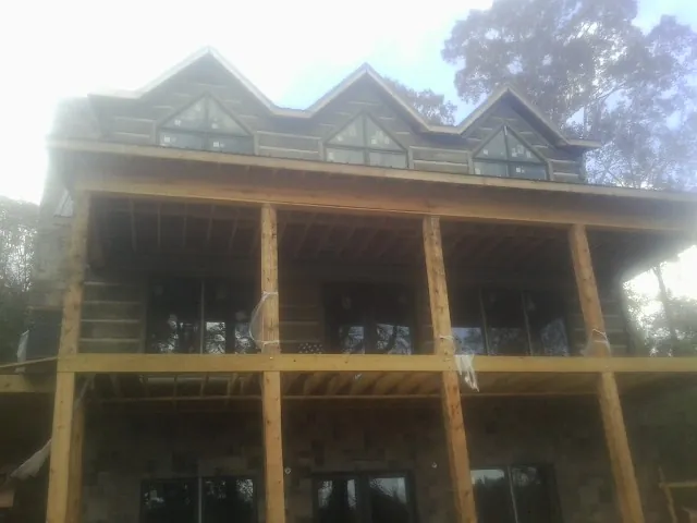 Dormers and porch framing on a large log home under construction — Roof Coating work by our crew in Herrick