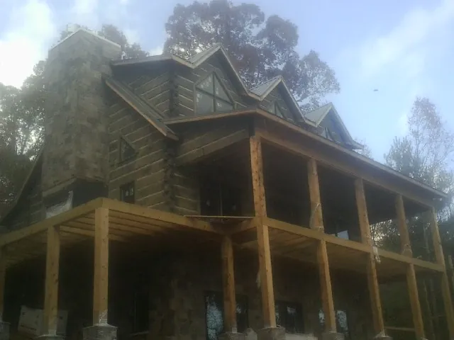 Stone chimney and dormers on a large log home with a timber porch in Herrick