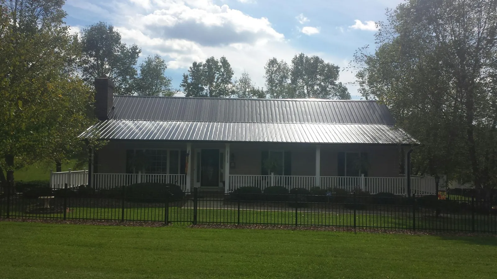 Gray metal roof on a brick ranch with a full width front porch — Gutter Guard Installation work by our crew in Herrick