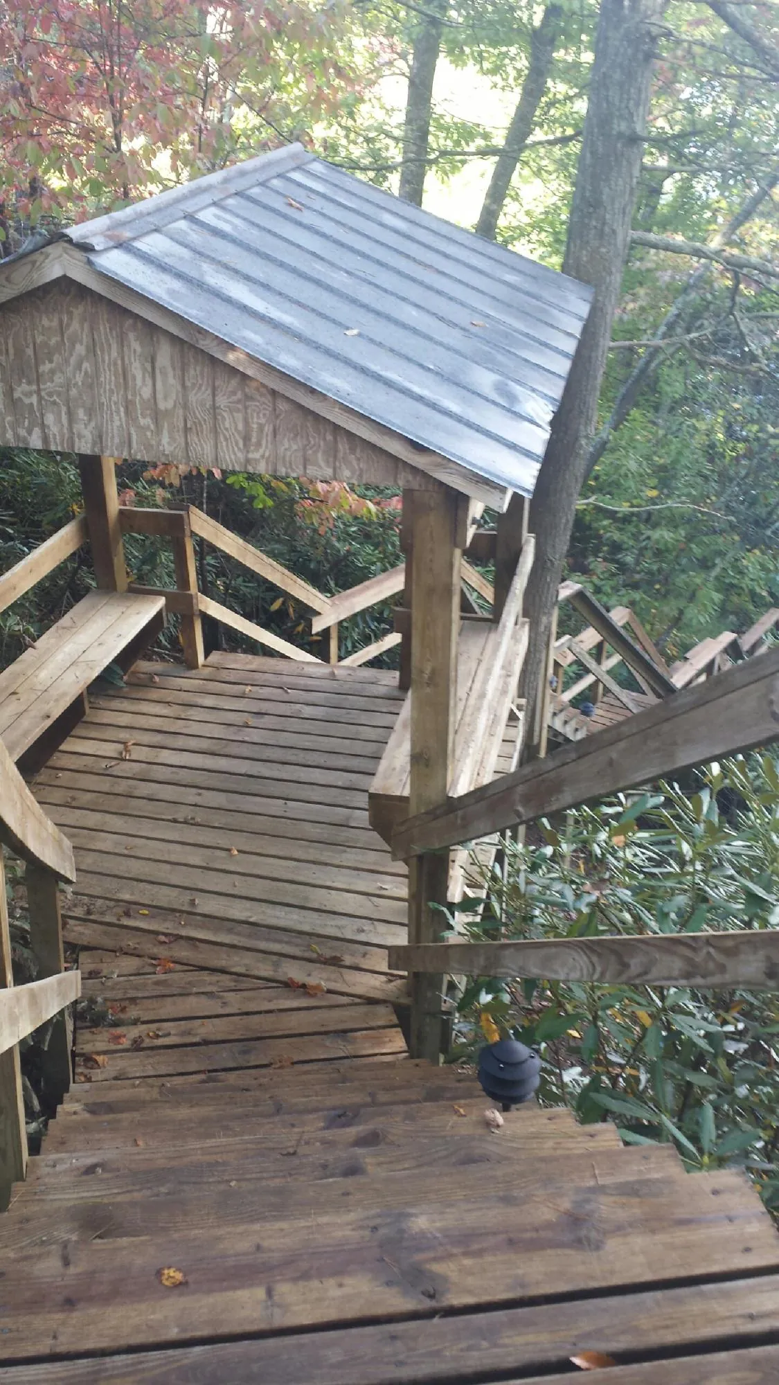 Metal roofed shelter over wooden steps on a wooded walkway — Skylight Repair & Installation work by our crew in Herrick