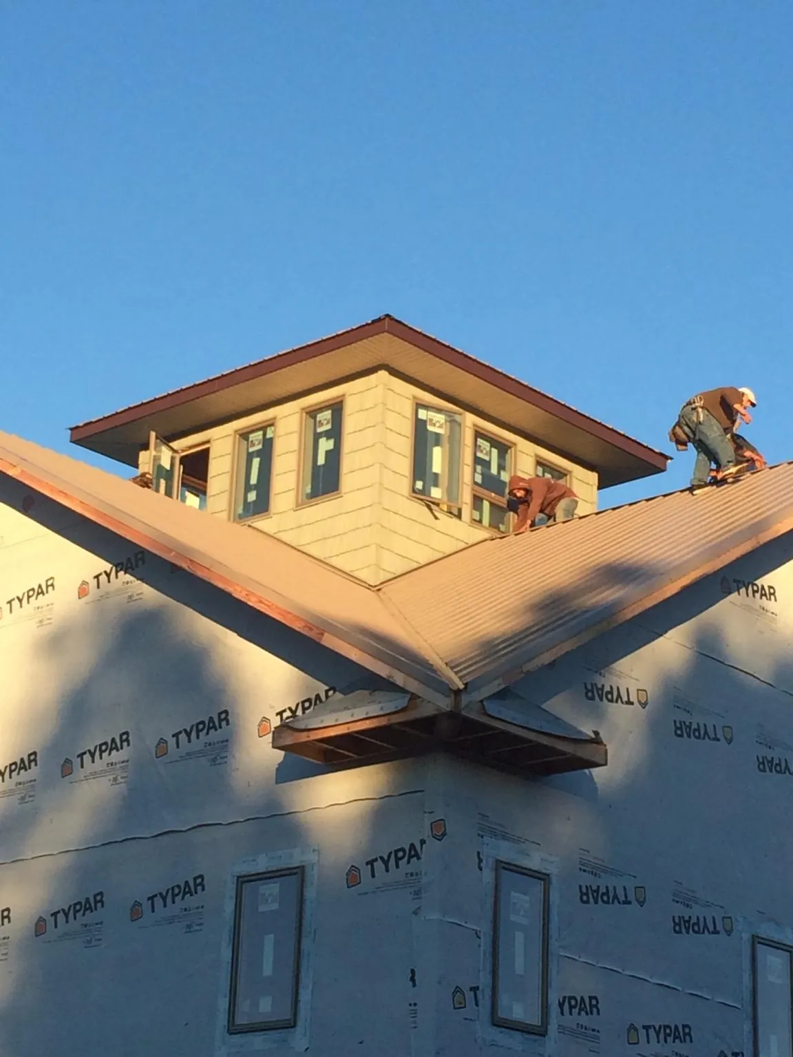 Roofers working around a rooftop cupola on a new metal roof at sunset — Roof Waterproofing in Herrick by Roofing Brothers